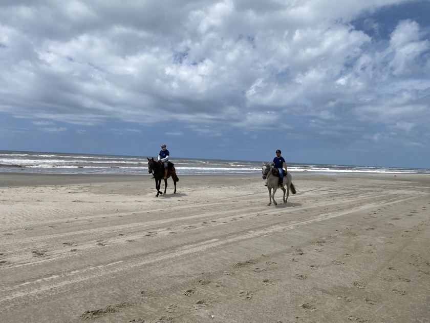 Twee ruiters op een breed zandstrand