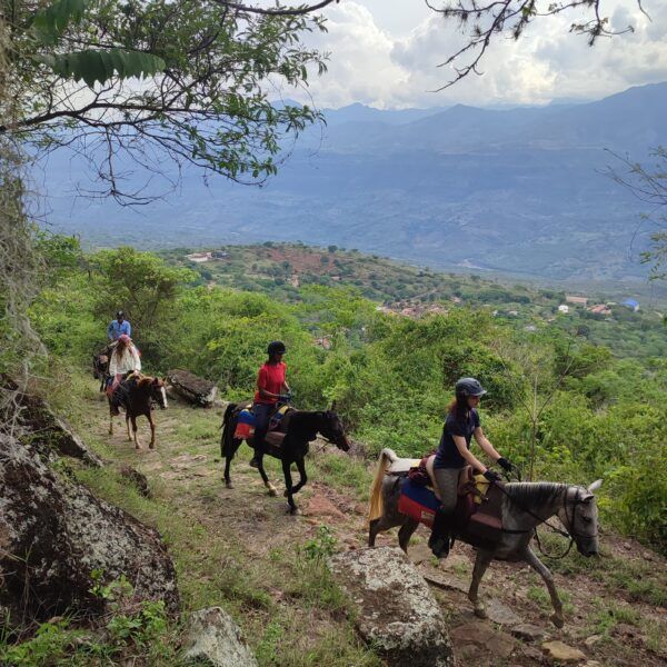 Ruiters op een bergpad met uitzicht over de groene heuvels van Colombia