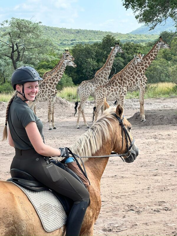 Lachende ruiter te paard tussen giraffes in Zuid-Afrika