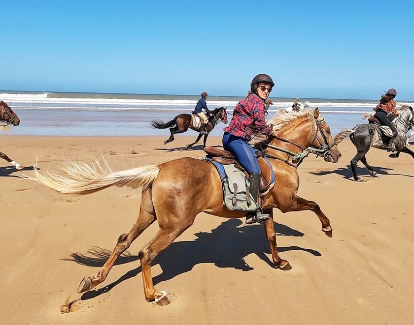 Ruiters in galop over een Marokkaans strand