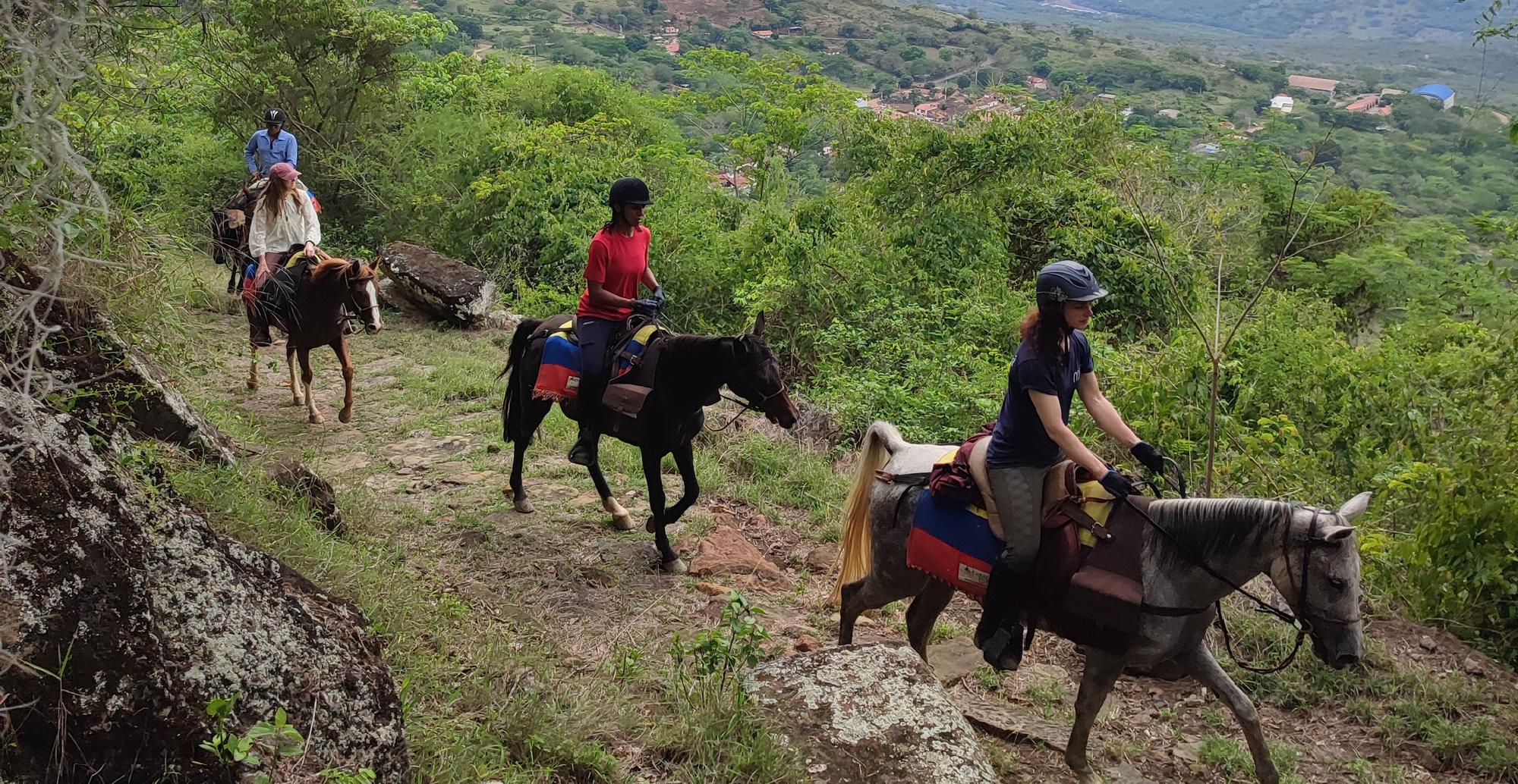 Drie ruiters op een bergpad door het groen bij Barichara, Colombia